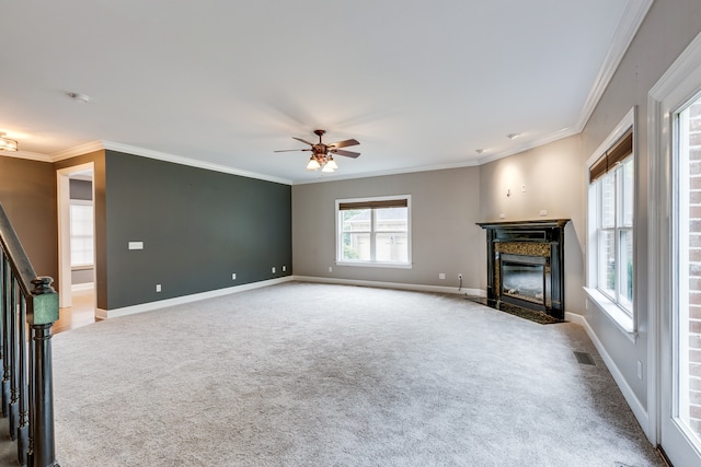 unfurnished living room featuring carpet flooring, crown molding, a high end fireplace, and ceiling fan