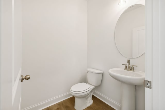 bathroom with toilet, wood-type flooring, and sink