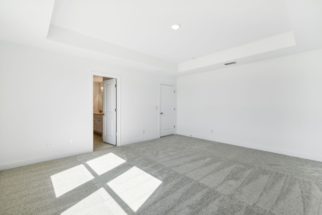 unfurnished room featuring light carpet and a tray ceiling