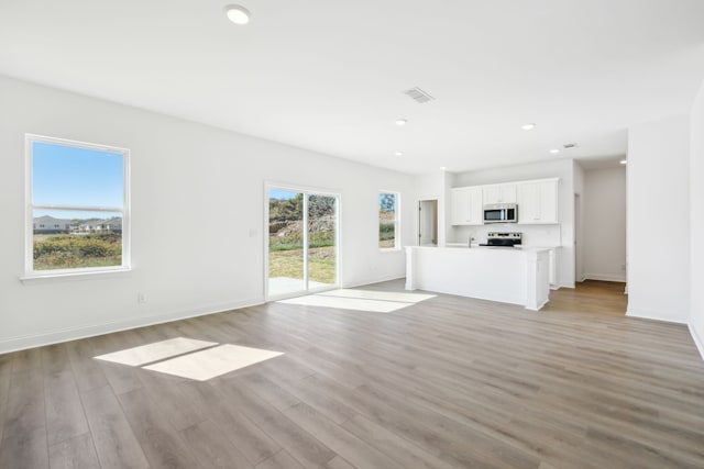 unfurnished living room with light hardwood / wood-style flooring and a healthy amount of sunlight