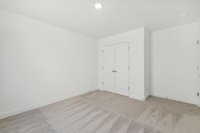 unfurnished bedroom featuring light colored carpet and a closet