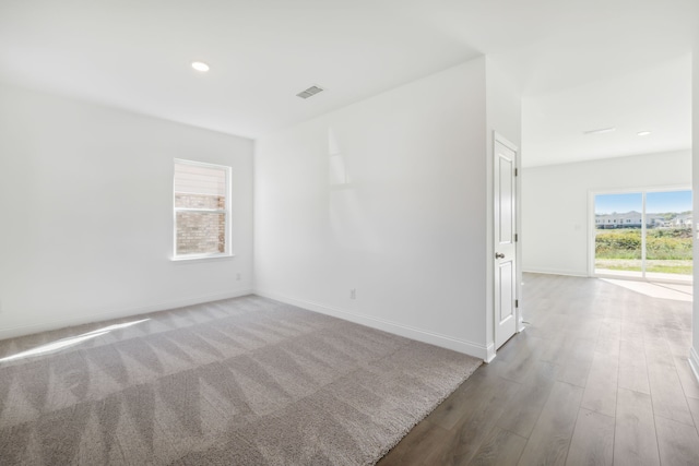 unfurnished room featuring wood-type flooring and a healthy amount of sunlight