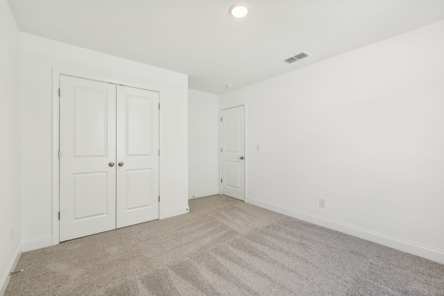 unfurnished bedroom featuring a closet and light colored carpet