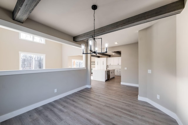 unfurnished dining area with beam ceiling, sink, light hardwood / wood-style flooring, and an inviting chandelier