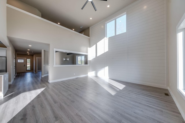 unfurnished living room with hardwood / wood-style floors, a wealth of natural light, and ceiling fan