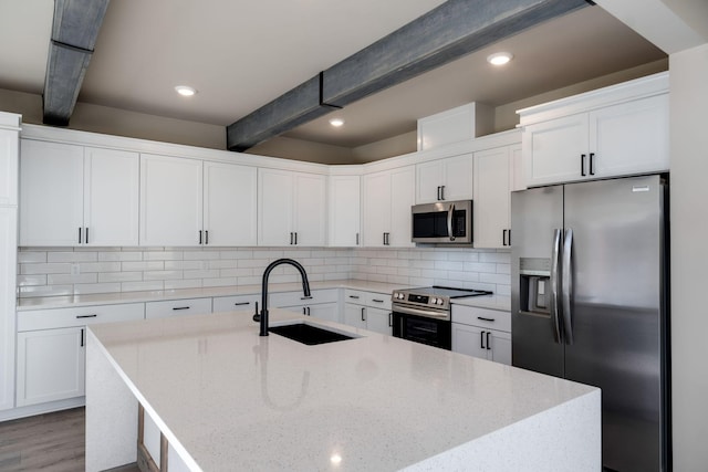 kitchen with beam ceiling, sink, backsplash, white cabinets, and appliances with stainless steel finishes