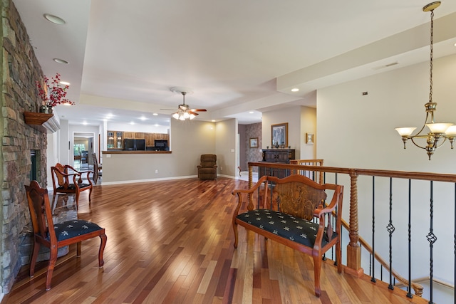 interior space featuring a fireplace, ceiling fan with notable chandelier, and hardwood / wood-style flooring
