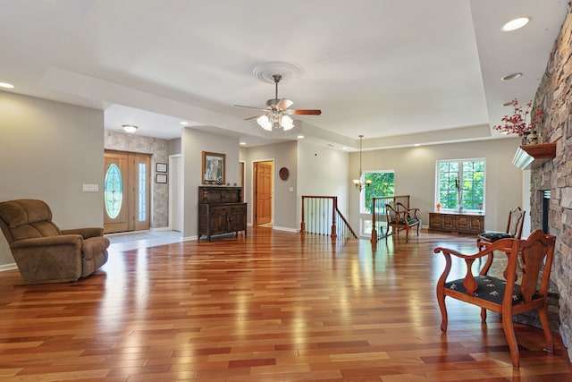 living room with a fireplace, light hardwood / wood-style floors, and ceiling fan with notable chandelier