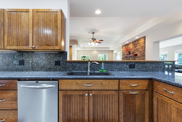 kitchen featuring ceiling fan, dishwasher, sink, tasteful backsplash, and dark stone counters