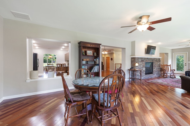 dining area with wood-type flooring and a stone fireplace