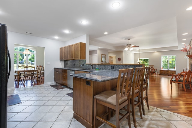 kitchen featuring black refrigerator, sink, ceiling fan, light tile patterned floors, and kitchen peninsula