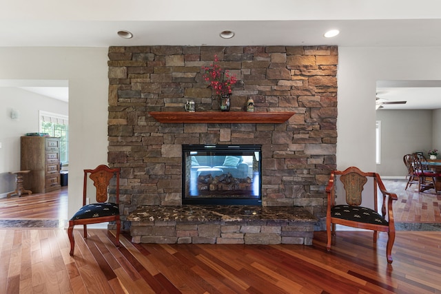 living room with ceiling fan, a fireplace, and wood-type flooring