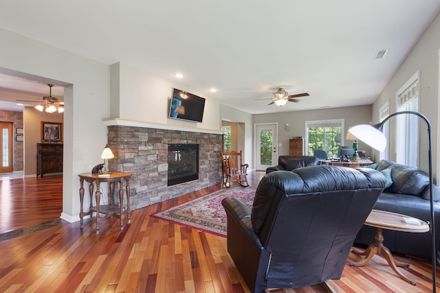living room with ceiling fan, wood-type flooring, and a fireplace