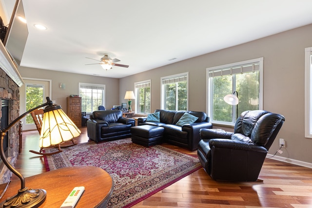 living room featuring ceiling fan, wood-type flooring, and a fireplace