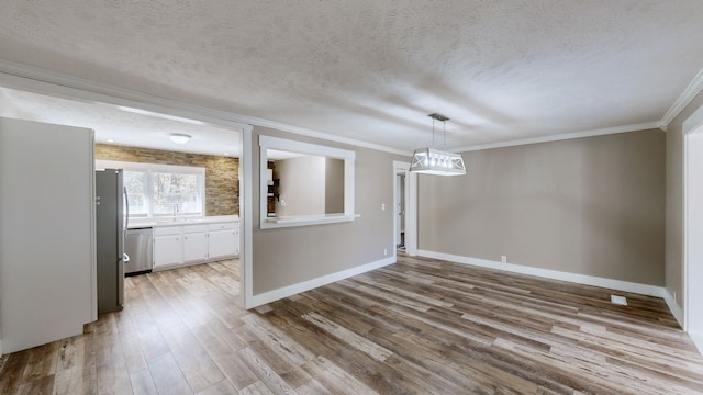 unfurnished dining area featuring light hardwood / wood-style flooring, a textured ceiling, and ornamental molding