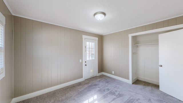 unfurnished bedroom with carpet, a closet, and wooden walls