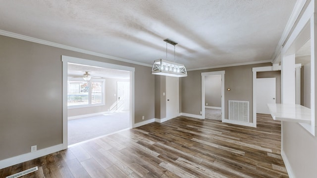 unfurnished dining area with ornamental molding, a textured ceiling, and dark wood-type flooring