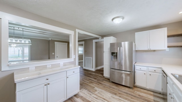 kitchen featuring white cabinetry, stainless steel fridge, crown molding, and light hardwood / wood-style floors