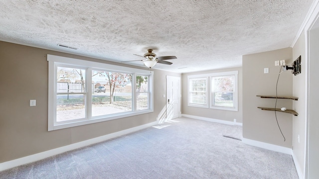 empty room with plenty of natural light, ceiling fan, light colored carpet, and a textured ceiling