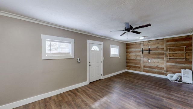 foyer with wooden walls, crown molding, and dark wood-type flooring