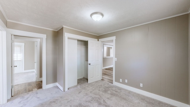 unfurnished bedroom with light colored carpet, ornamental molding, a textured ceiling, and a closet