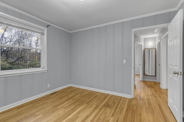 spare room featuring light wood-type flooring and crown molding