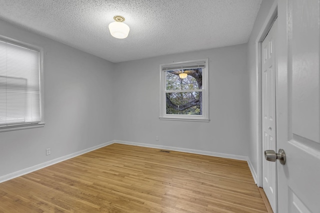 spare room with a textured ceiling and light wood-type flooring