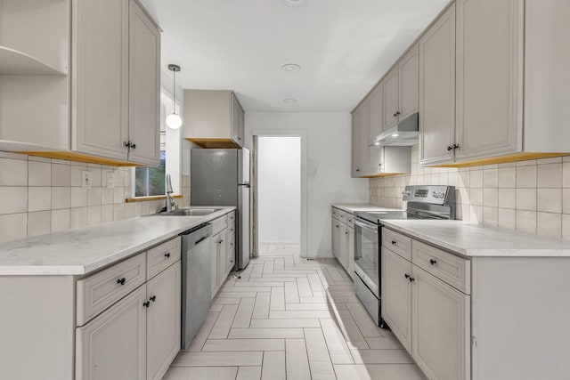 kitchen featuring tasteful backsplash, stainless steel appliances, hanging light fixtures, and sink