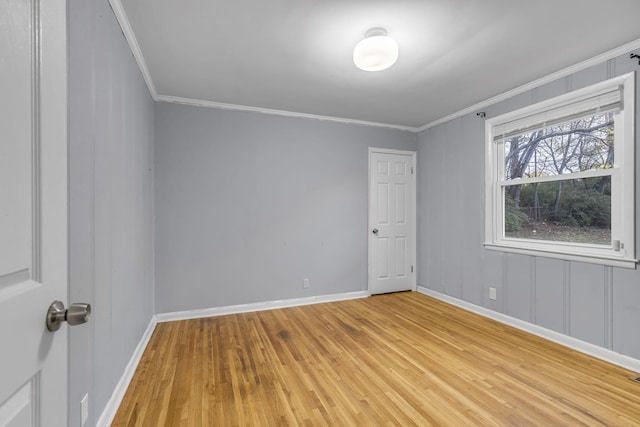 empty room with crown molding and light hardwood / wood-style flooring