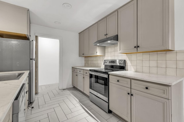 kitchen featuring sink, gray cabinets, tasteful backsplash, light stone counters, and stainless steel appliances