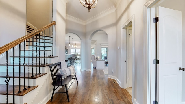 hall with hardwood / wood-style flooring, ornamental molding, a high ceiling, and an inviting chandelier