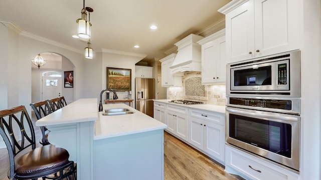 kitchen with appliances with stainless steel finishes, a kitchen island with sink, sink, decorative light fixtures, and a breakfast bar area