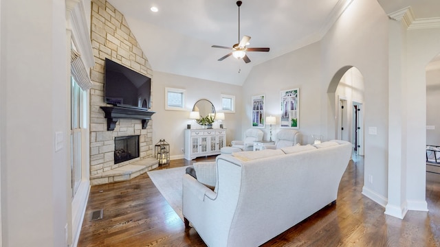 living room featuring ceiling fan, crown molding, high vaulted ceiling, dark hardwood / wood-style floors, and a stone fireplace