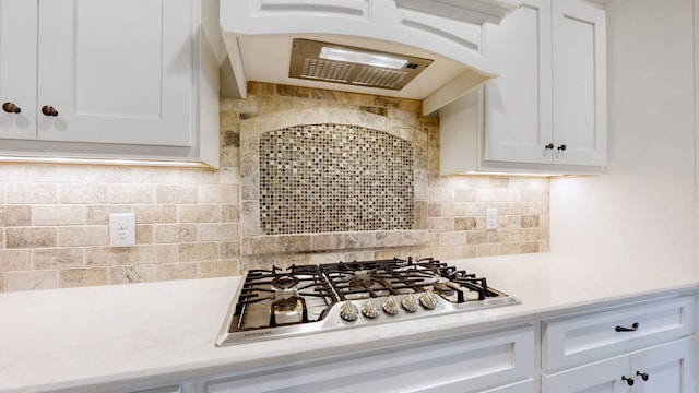 kitchen featuring white cabinets, stainless steel gas stovetop, custom range hood, and tasteful backsplash