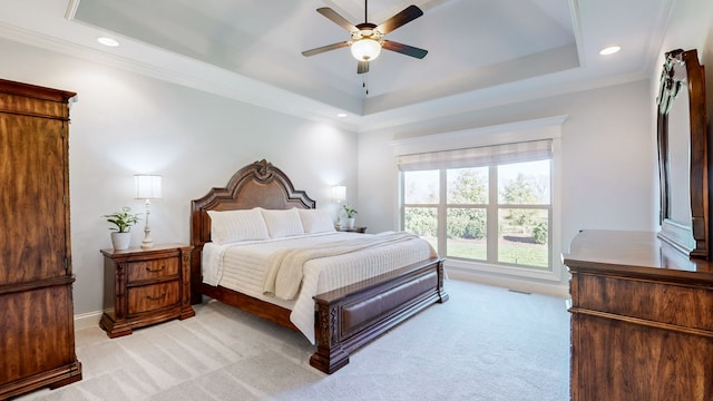 bedroom featuring ceiling fan, ornamental molding, light carpet, and a tray ceiling