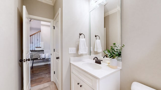 bathroom with toilet, vanity, wood-type flooring, and ornamental molding