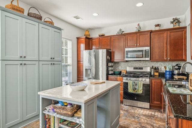 kitchen with backsplash, dark stone counters, sink, a kitchen island, and stainless steel appliances