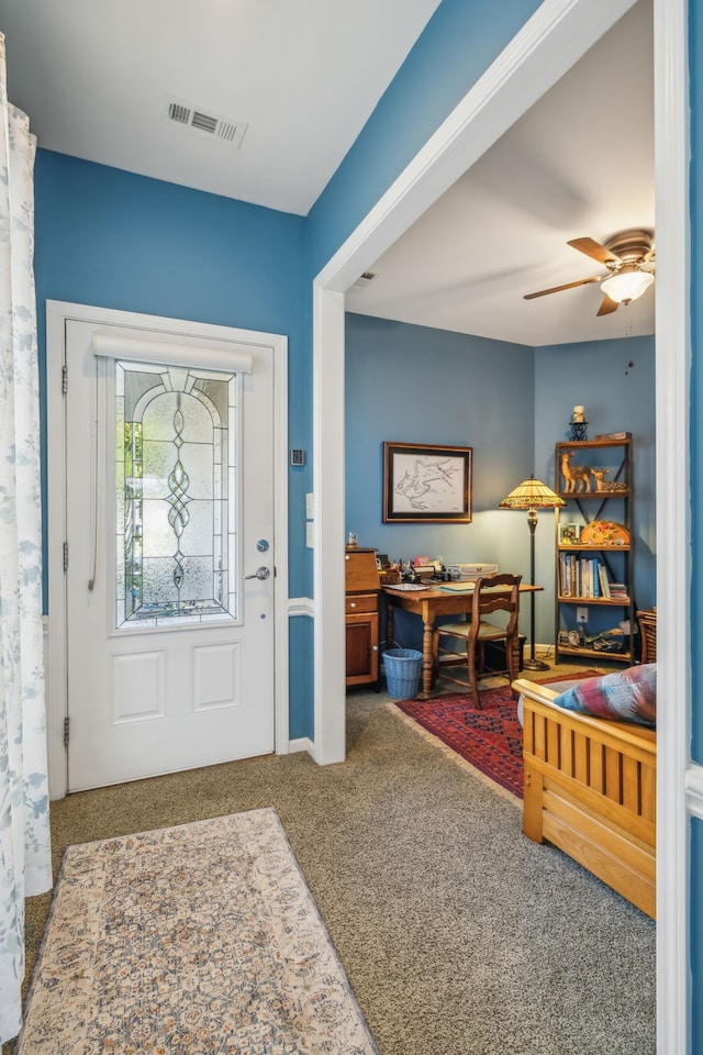 foyer with ceiling fan and carpet floors