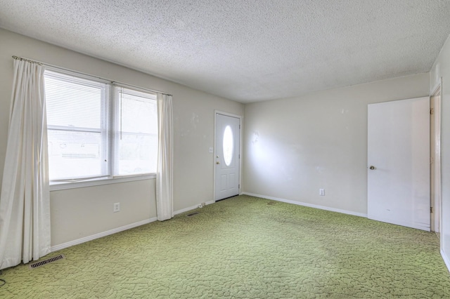 carpeted foyer entrance with a textured ceiling