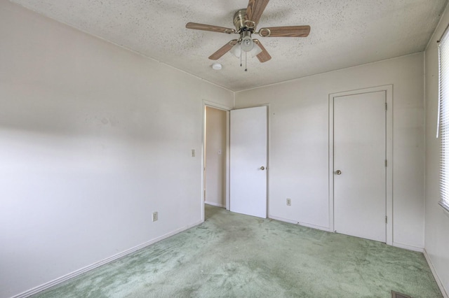 unfurnished bedroom featuring ceiling fan, light colored carpet, and a textured ceiling