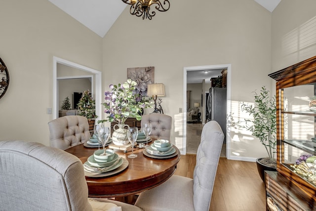 dining room featuring hardwood / wood-style floors, high vaulted ceiling, and an inviting chandelier