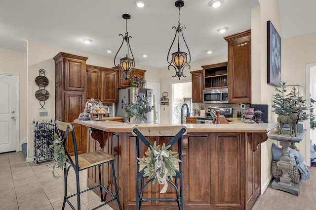 kitchen featuring kitchen peninsula, appliances with stainless steel finishes, sink, light tile patterned floors, and decorative light fixtures