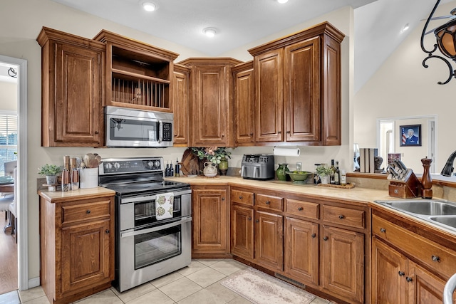 kitchen featuring light tile patterned floors, stainless steel appliances, lofted ceiling, and sink