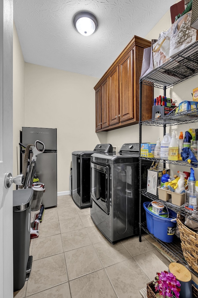 washroom featuring cabinets, light tile patterned floors, a textured ceiling, and separate washer and dryer