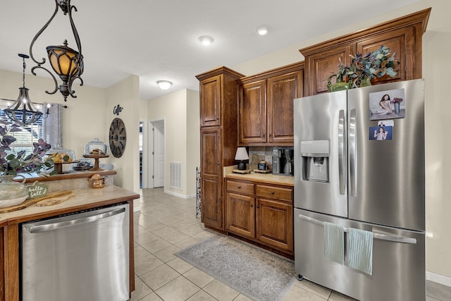 kitchen featuring decorative light fixtures, light tile patterned floors, appliances with stainless steel finishes, and an inviting chandelier