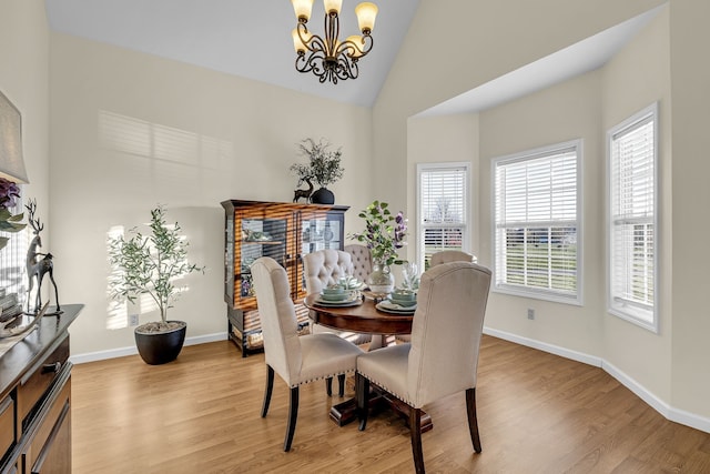 dining area featuring light wood-type flooring, high vaulted ceiling, and an inviting chandelier