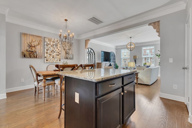 kitchen featuring a center island, hanging light fixtures, light hardwood / wood-style flooring, a breakfast bar, and ornamental molding