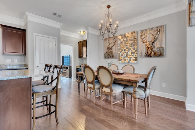 dining room with hardwood / wood-style flooring, a notable chandelier, and ornamental molding