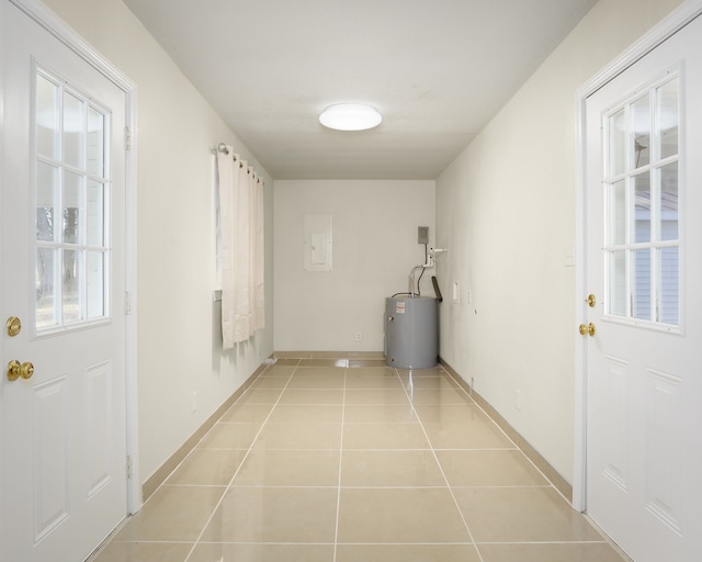 corridor featuring a healthy amount of sunlight, light tile patterned flooring, and electric water heater