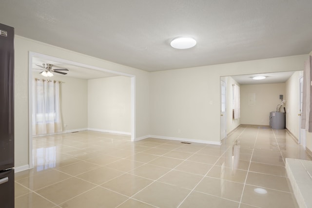 tiled empty room featuring a textured ceiling, electric water heater, and ceiling fan